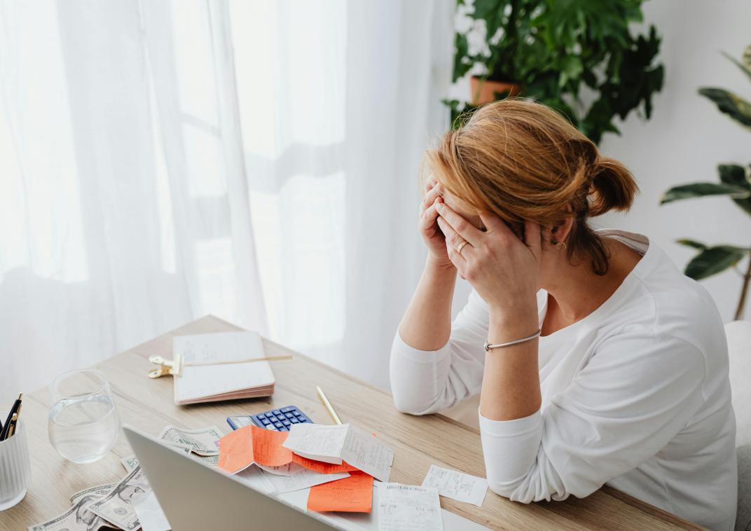 Vrouw met handen in het haar achter bureau.