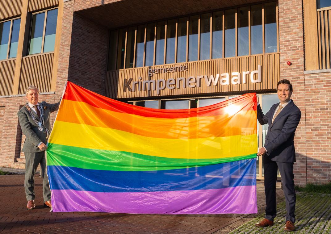 Burgemeester Hans Beenhakker en wethouder Sandro Kovačić hijsen de regenboogvlag