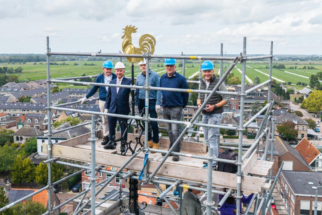 De haan wordt teruggezet op de toren.