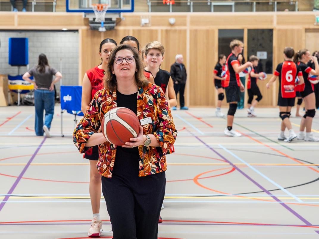 Wethouder Irma Bultman in actie met een basketbal.